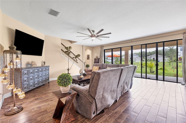 living room featuring plenty of natural light, a textured ceiling, stairs, and wood finished floors