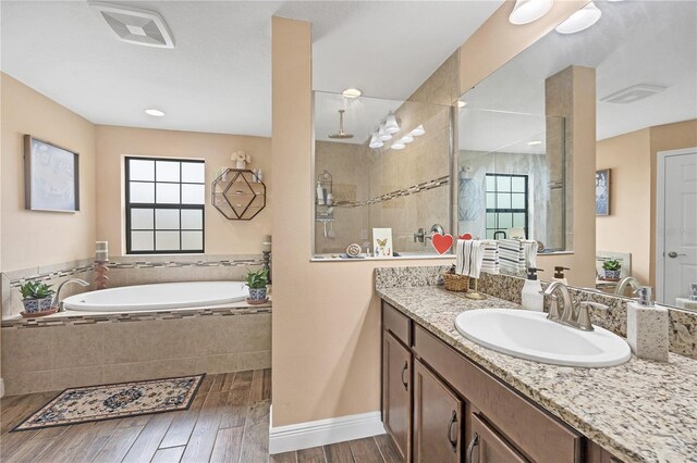 bathroom featuring vanity, wood finished floors, visible vents, tiled shower, and a garden tub