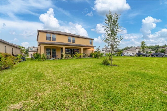 back of house with a lawn, fence, and stucco siding