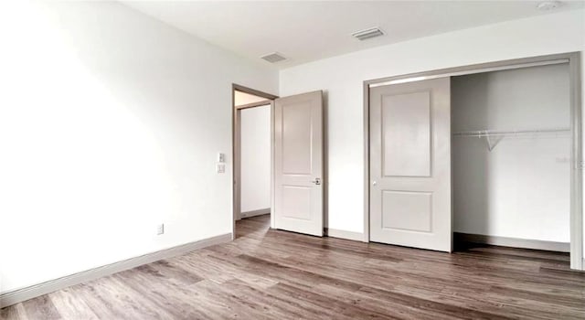 unfurnished bedroom featuring wood-type flooring and a closet