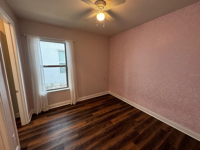 spare room with a textured ceiling, dark hardwood / wood-style floors, and ceiling fan