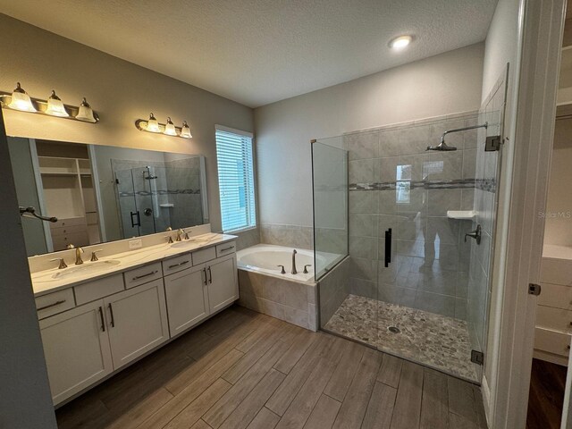 bathroom featuring vanity, hardwood / wood-style floors, plus walk in shower, and a textured ceiling