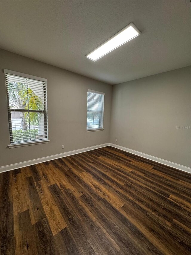 empty room with dark wood-type flooring and a wealth of natural light