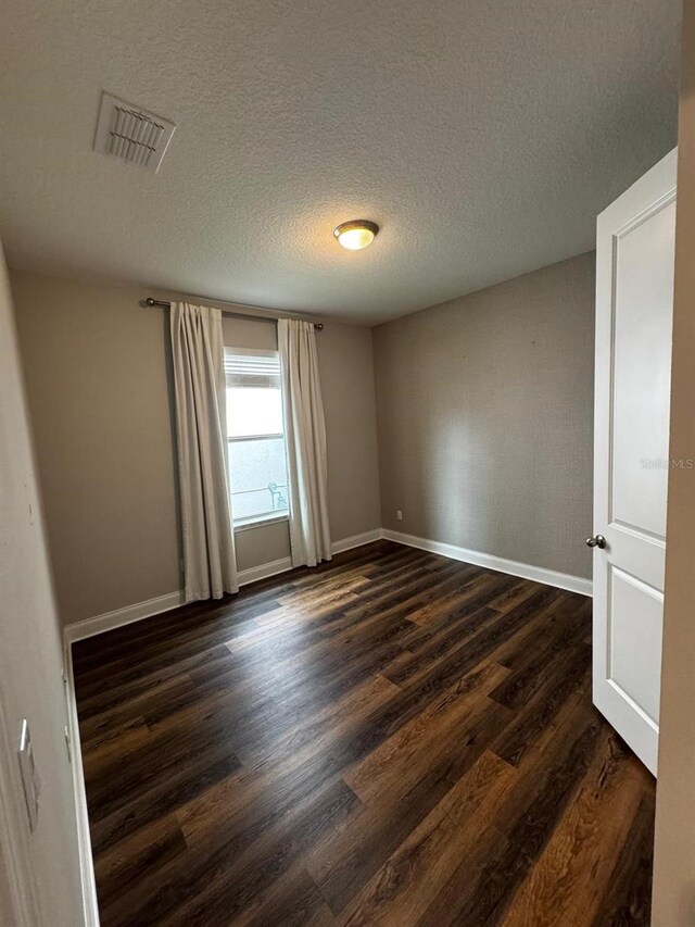 spare room with dark hardwood / wood-style floors and a textured ceiling