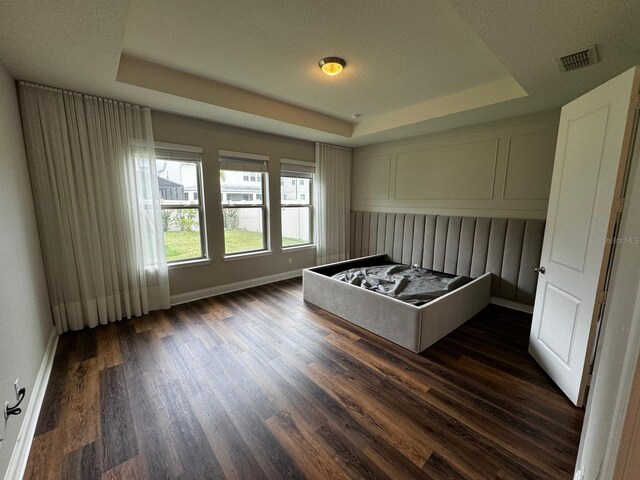 unfurnished bedroom with dark hardwood / wood-style floors and a raised ceiling