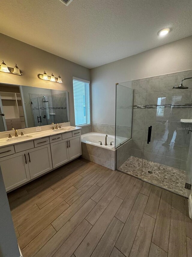 bathroom featuring vanity, a textured ceiling, and plus walk in shower