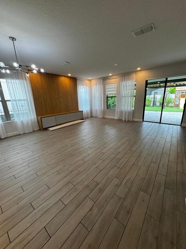 interior space featuring wooden walls, a textured ceiling, and light wood-type flooring