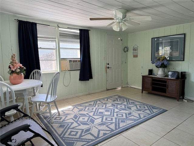 interior space with ceiling fan, wood walls, and light tile patterned flooring