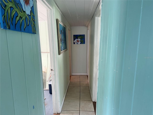 hallway featuring wooden walls and light tile patterned floors