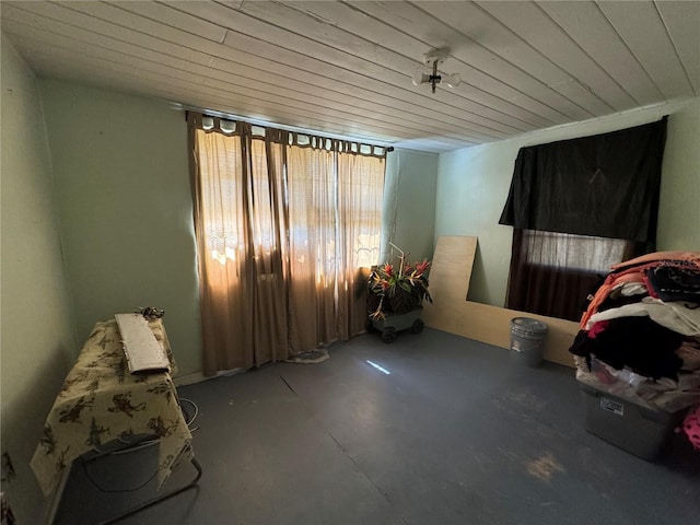 unfurnished room with wooden ceiling and concrete floors