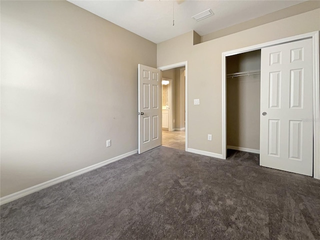 unfurnished bedroom with a closet and dark colored carpet