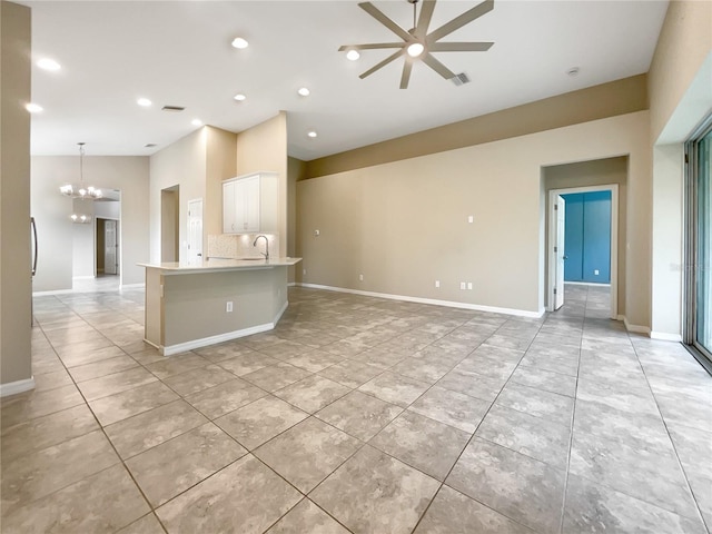 kitchen with an island with sink, decorative backsplash, white cabinetry, decorative light fixtures, and ceiling fan with notable chandelier