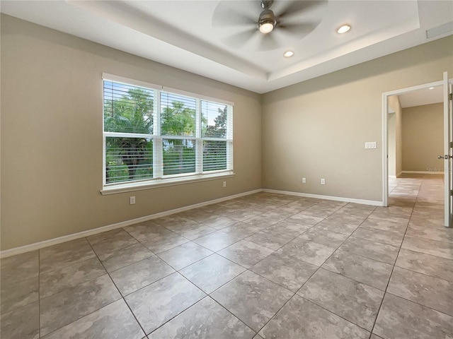 tiled spare room with a raised ceiling and ceiling fan