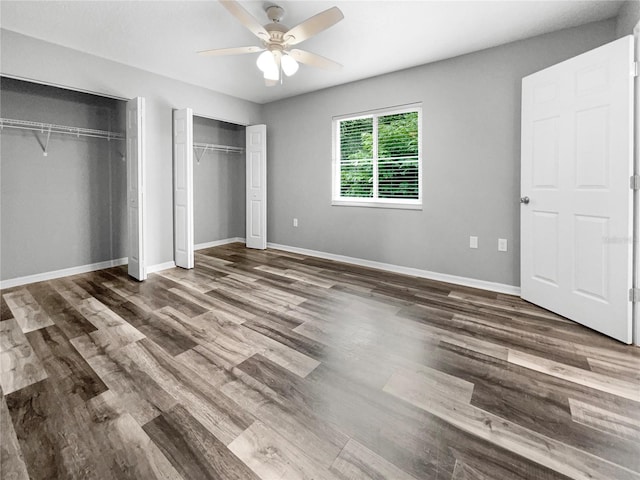 unfurnished bedroom featuring hardwood / wood-style flooring, two closets, and ceiling fan