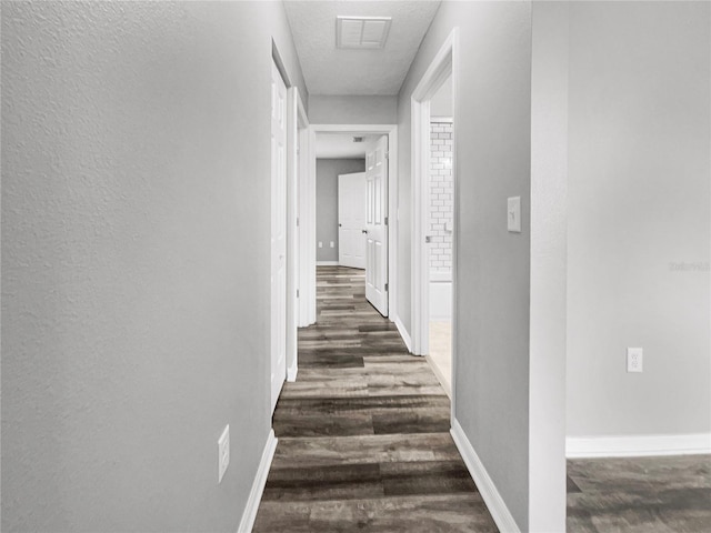 hall with a textured ceiling and dark hardwood / wood-style floors