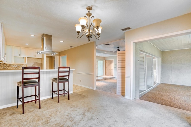 kitchen with a breakfast bar, white cabinets, backsplash, island exhaust hood, and light carpet