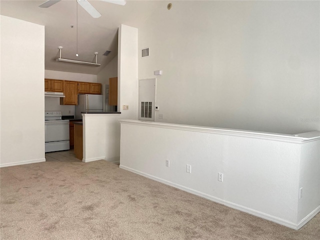 kitchen with visible vents, light carpet, electric stove, brown cabinetry, and freestanding refrigerator