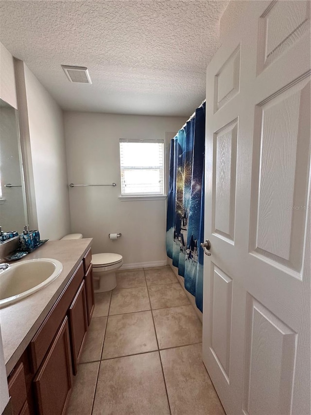 bathroom with tile patterned flooring, vanity, toilet, and a textured ceiling