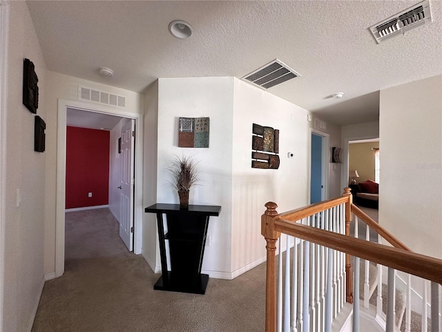 hallway with a textured ceiling and dark carpet