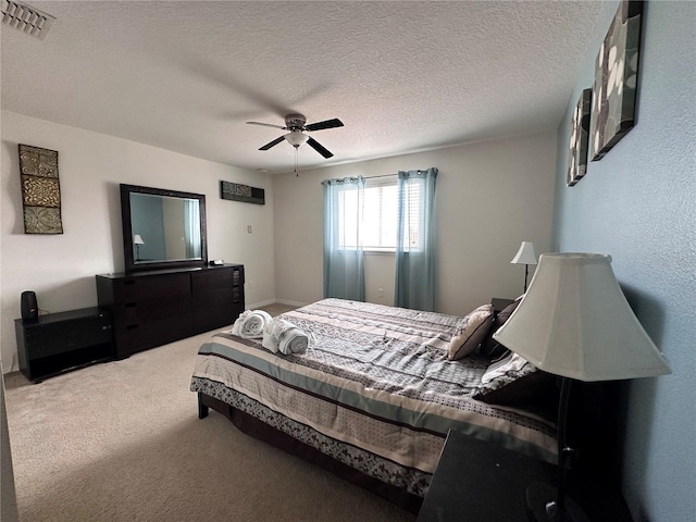 carpeted bedroom featuring ceiling fan and a textured ceiling