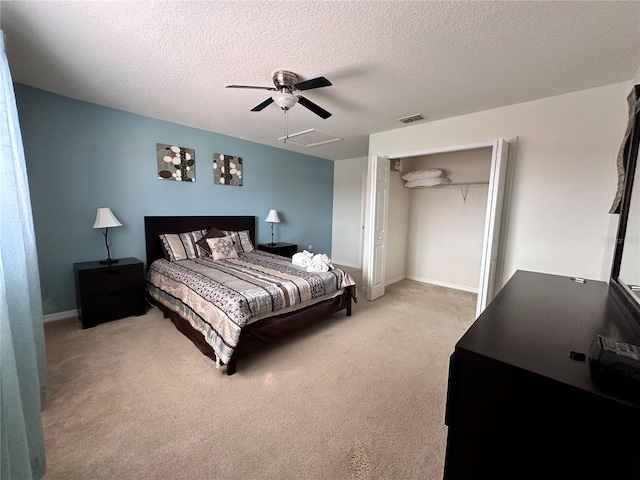 bedroom featuring a textured ceiling, a closet, ceiling fan, and light colored carpet