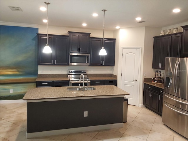 kitchen with sink, decorative light fixtures, stainless steel appliances, and a center island with sink