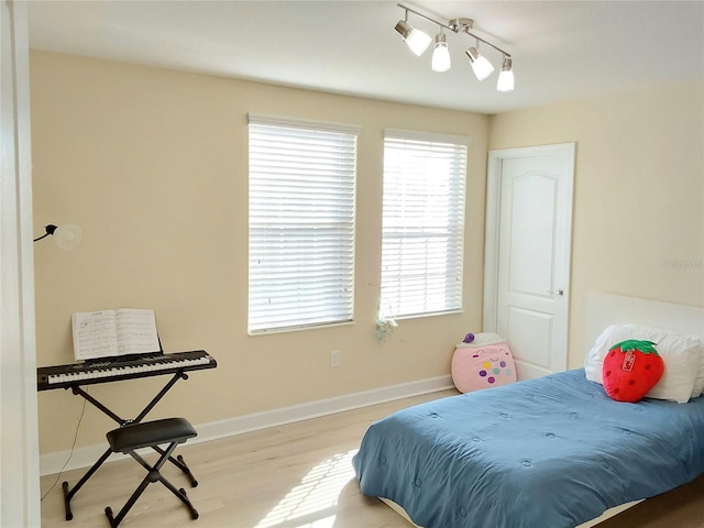 bedroom with track lighting and light wood-type flooring