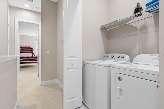 clothes washing area featuring light carpet and washer and dryer