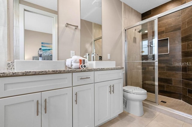 bathroom featuring a shower with shower door, vanity, tile patterned floors, and toilet