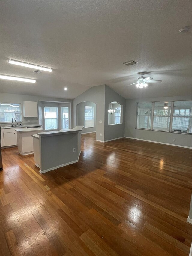 kitchen with hardwood / wood-style flooring, a kitchen island, lofted ceiling, white cabinetry, and ceiling fan