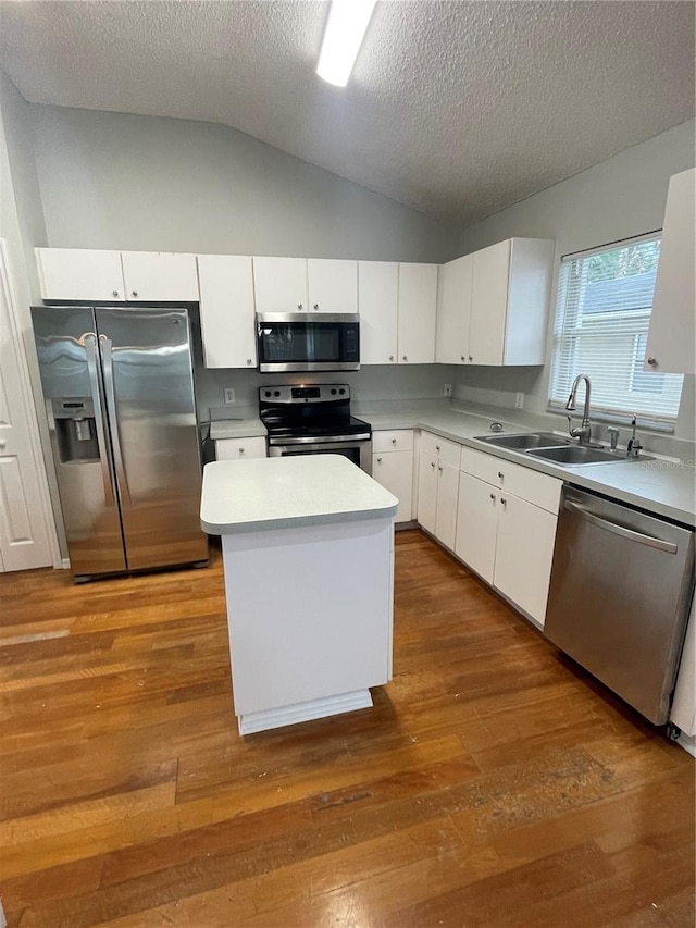 kitchen featuring white cabinets, stainless steel appliances, hardwood / wood-style flooring, vaulted ceiling, and sink