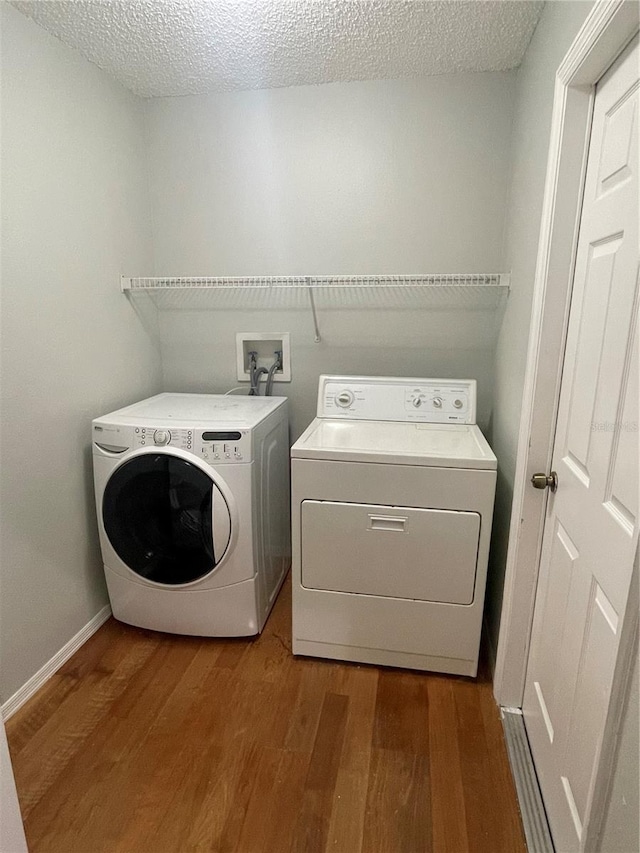 laundry area with hardwood / wood-style flooring, washer and clothes dryer, and a textured ceiling