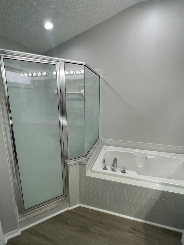 bathroom with hardwood / wood-style flooring, shower with separate bathtub, and a textured ceiling