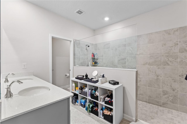 bathroom with vanity and a tile shower