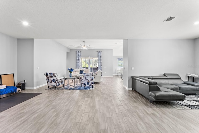 living room featuring light hardwood / wood-style flooring, a textured ceiling, and ceiling fan