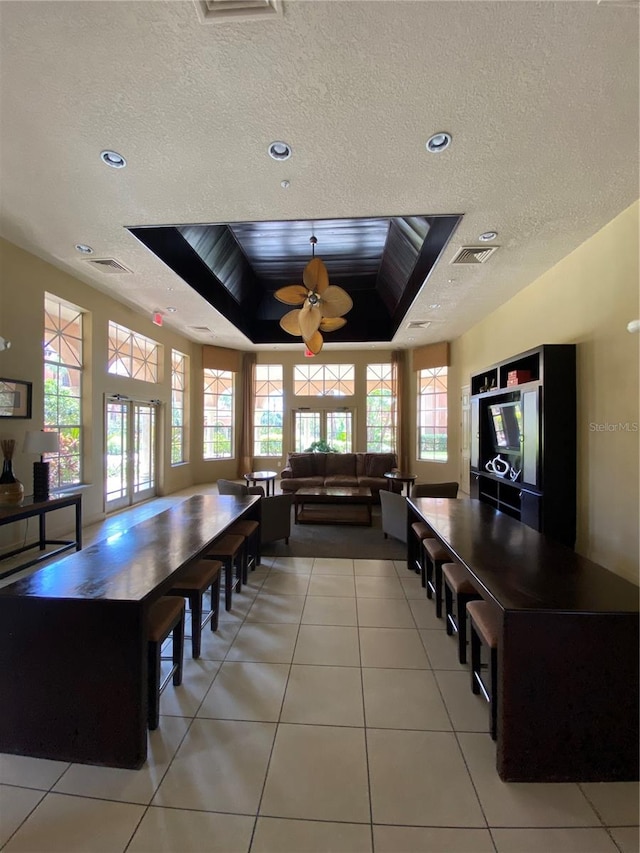 dining area with ceiling fan, light tile patterned floors, plenty of natural light, and a tray ceiling