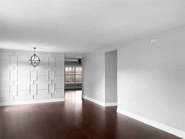 unfurnished room featuring a textured ceiling, ceiling fan with notable chandelier, and dark hardwood / wood-style floors