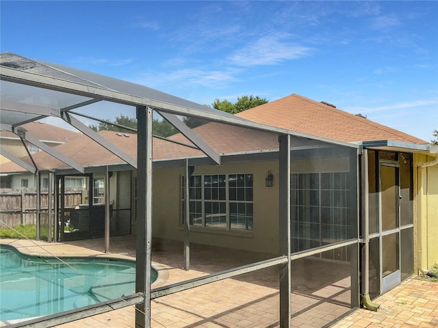 rear view of property featuring glass enclosure and a patio