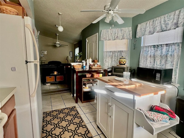 kitchen featuring white fridge, white cabinets, a center island, ceiling fan, and vaulted ceiling