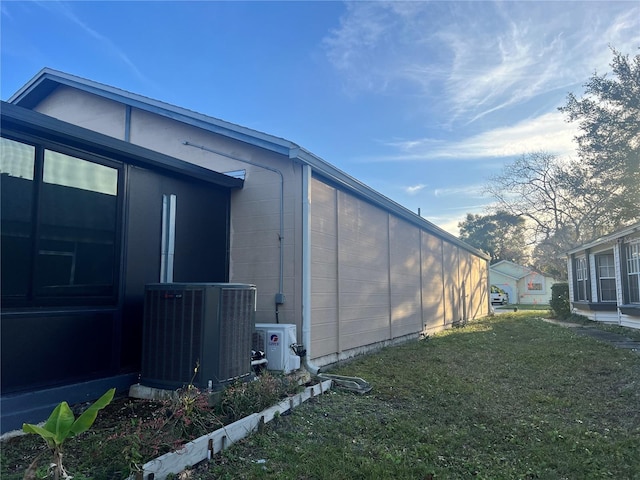 view of side of property with central air condition unit and a lawn