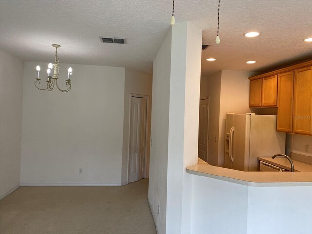 kitchen featuring decorative light fixtures, white fridge with ice dispenser, an inviting chandelier, light colored carpet, and a textured ceiling