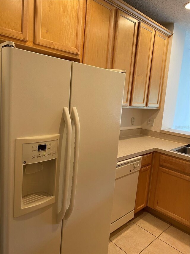 kitchen featuring a textured ceiling, white appliances, and light tile patterned floors