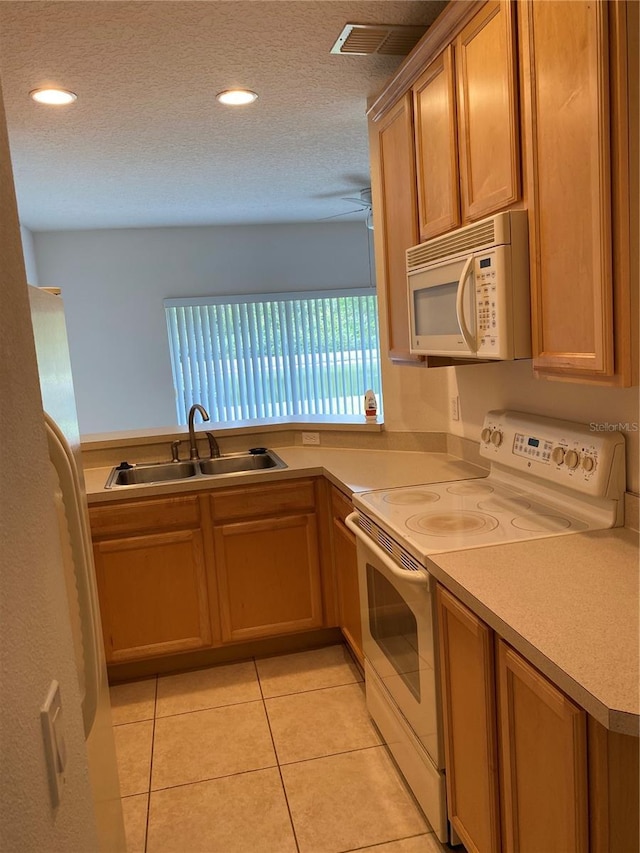 kitchen featuring sink, white appliances, a textured ceiling, and light tile patterned flooring