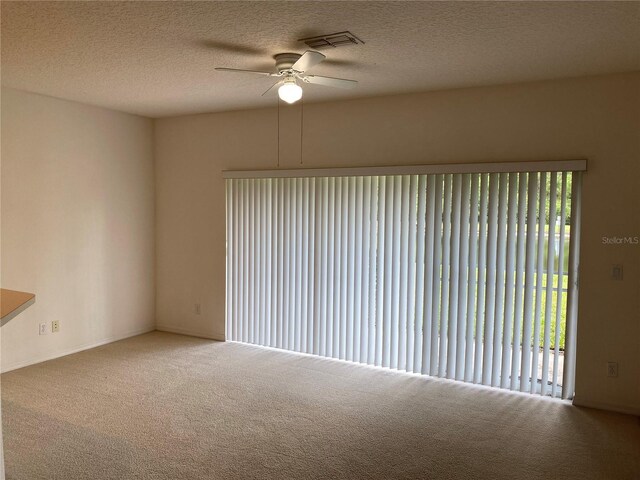 carpeted empty room with a textured ceiling, a wealth of natural light, and ceiling fan