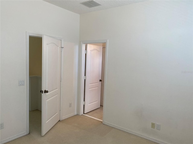 unfurnished bedroom featuring light carpet and a textured ceiling