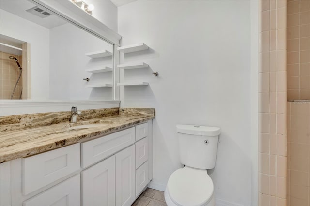 bathroom with a tile shower, tile patterned flooring, vanity, and toilet