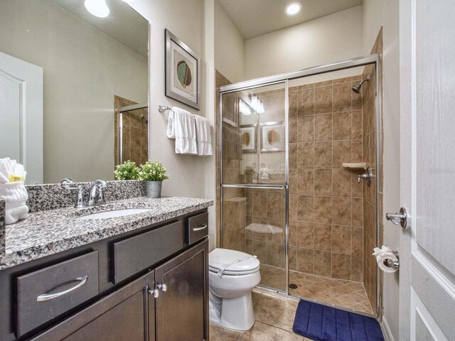 bathroom with tile patterned floors, toilet, vanity, and an enclosed shower