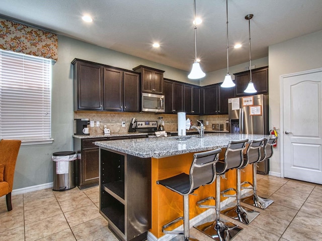 kitchen with a kitchen island with sink, stainless steel appliances, and tasteful backsplash