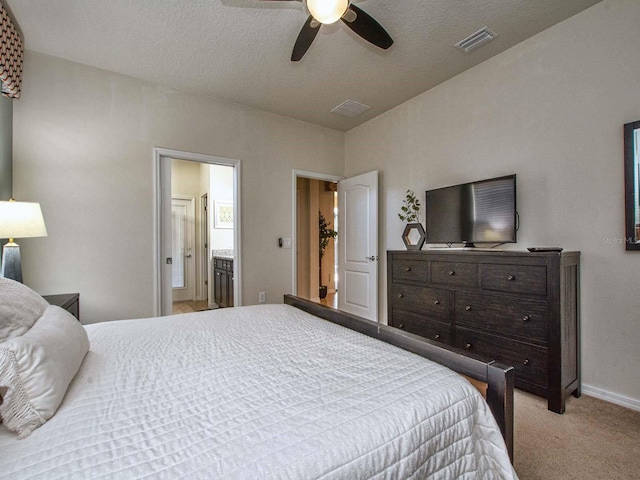 bedroom with ensuite bath, light carpet, ceiling fan, and a textured ceiling