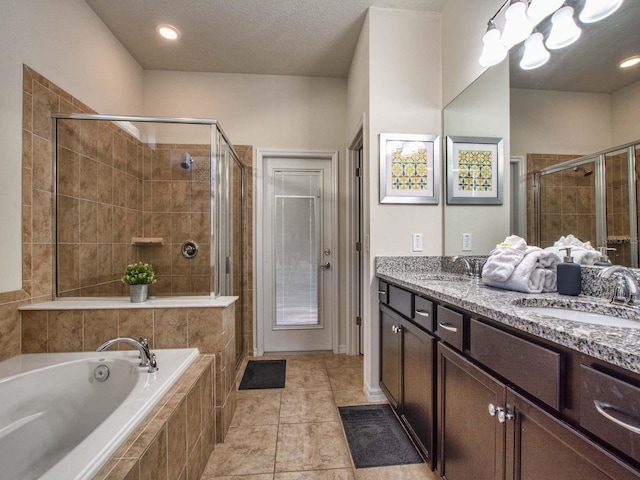 bathroom with plus walk in shower, tile patterned floors, a textured ceiling, and double vanity